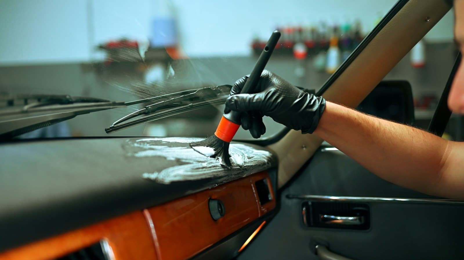 Detailer cleaning a dashboard with a soft detailing brush