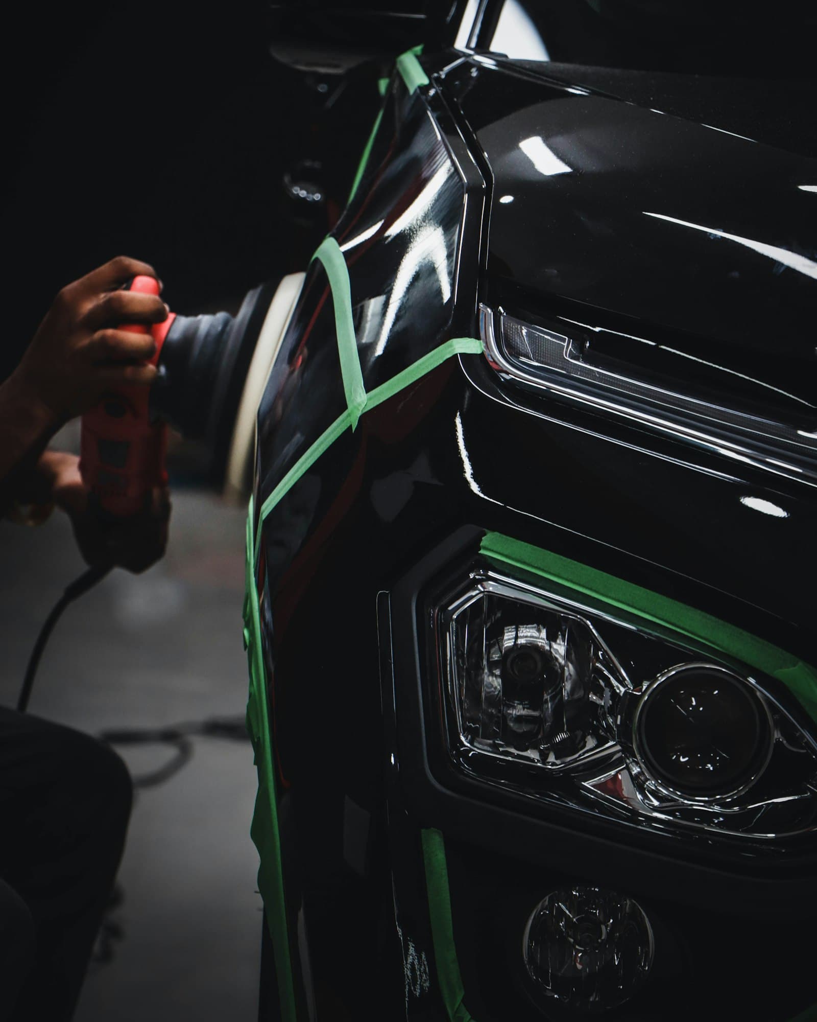Detailer polishing the front panel of a black car
